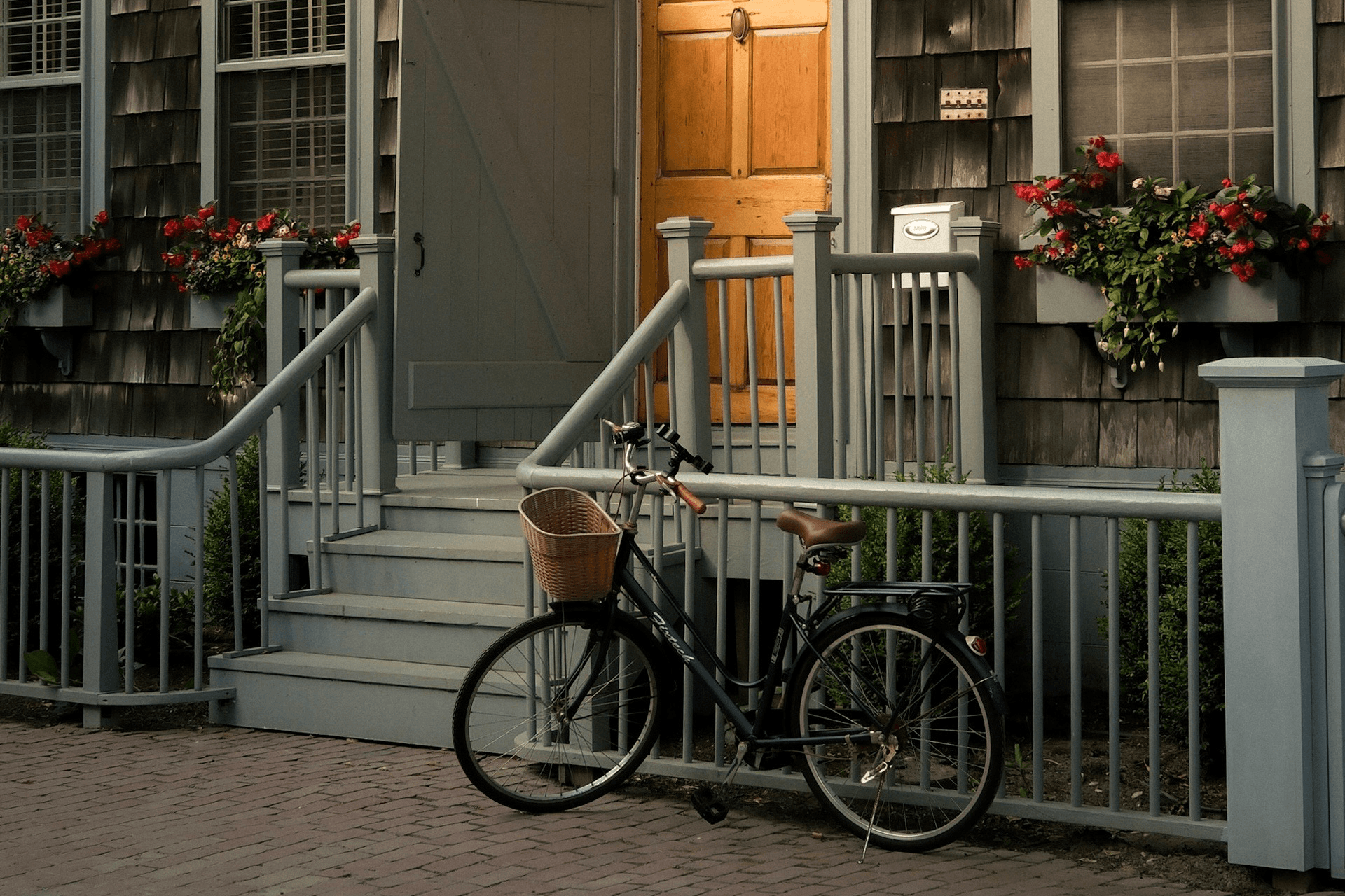 A bicycle is parked near a wooden porch with flowers and a wooden door.